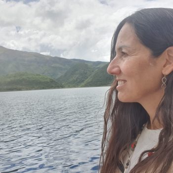 Mariví Perlor mirando el agua de un lago rodeado de montañas