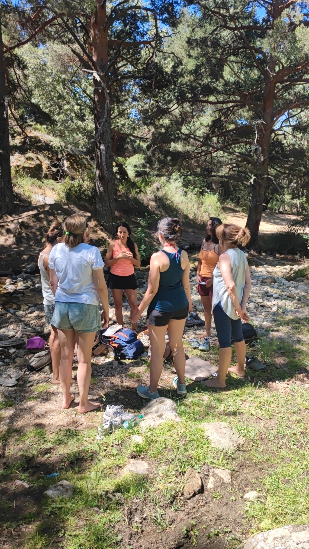 Mariví Perlor conversando con un grupo de mujeres en un claro del bosque junto a un arroyo