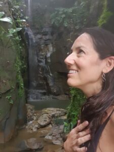 Mariví Perlor sonriendo frente a una cascada entre musgo y roca