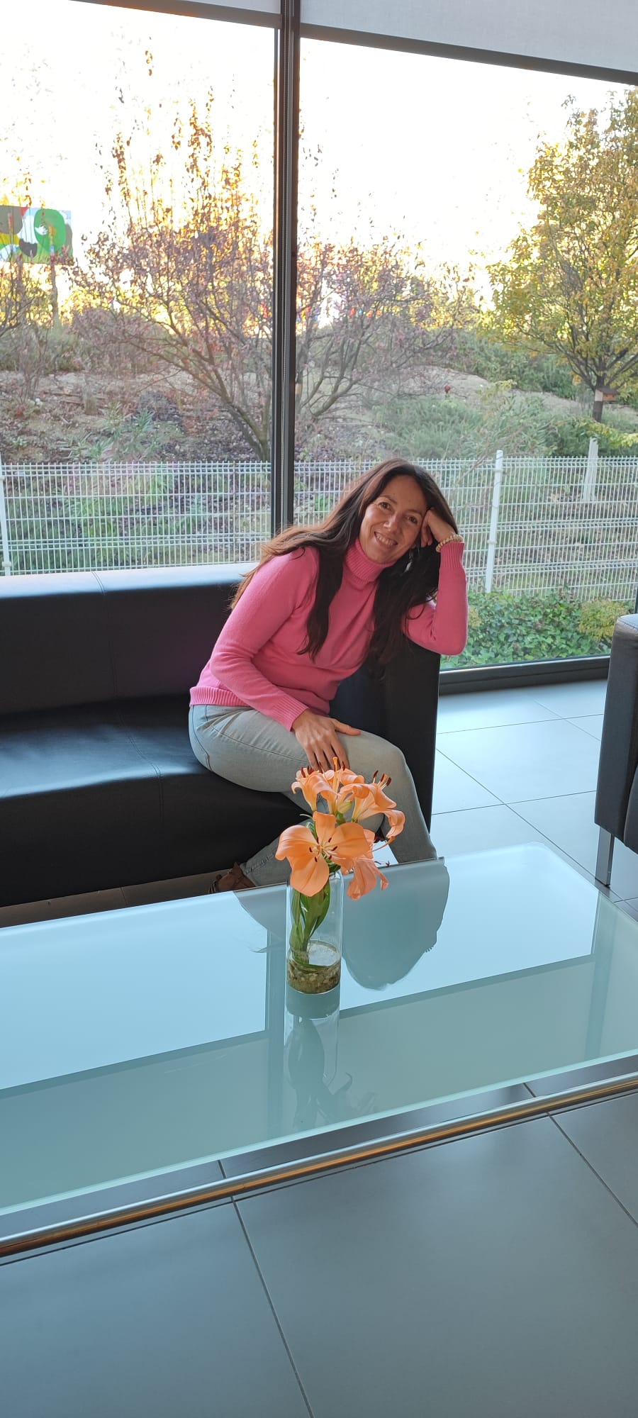 Mariví Perlor sentada junto a una ventana, con flores en primer plano