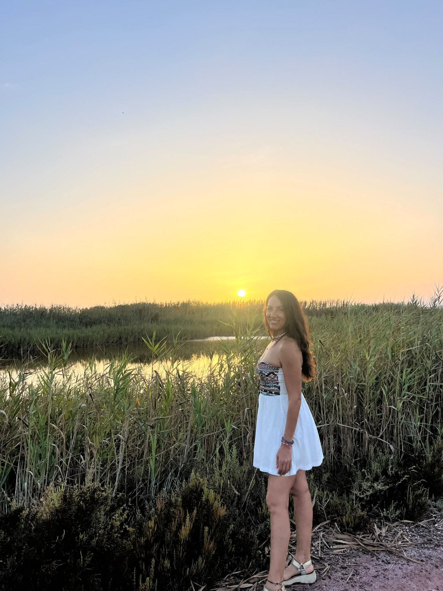 Mariví Perlor sonriendo junto a un lago al atardecer, entre cañas